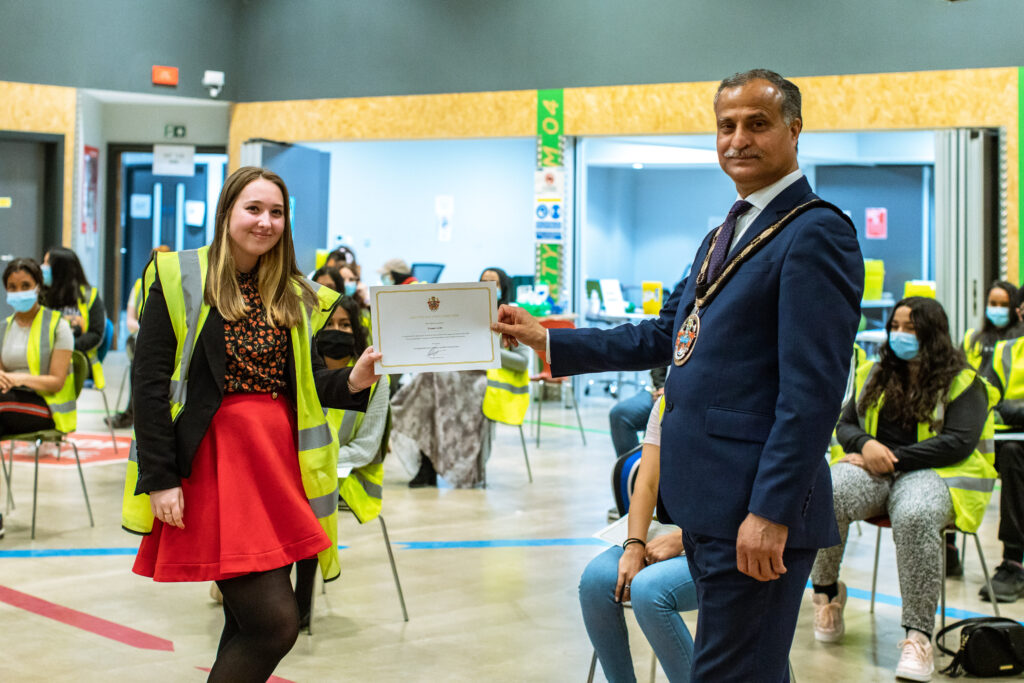 A young person is presented with a certificate by the Mayor.